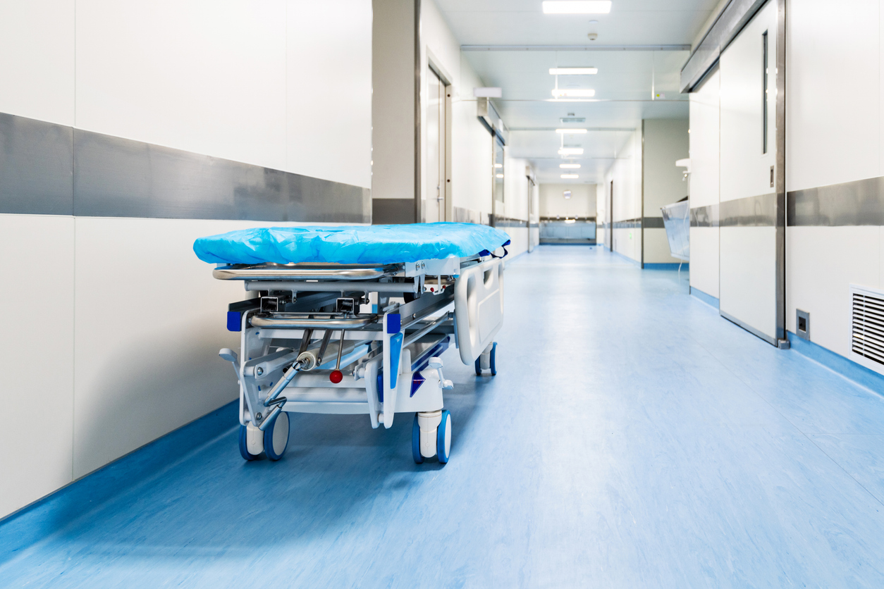 Empty hospital bed in empty hospital corridor