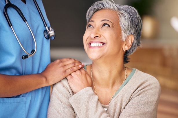 happy female hospital patient, nurse's hand on patient's shoulder