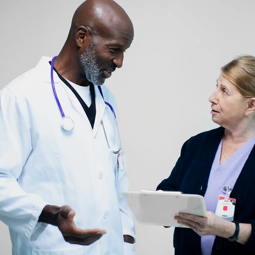 Hospital physician and nurse reviewing operational data on a tablet — illustrating real-time clinical decision-making.