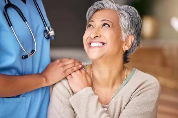 happy female hospital patient, nurse's hand on patient's shoulder