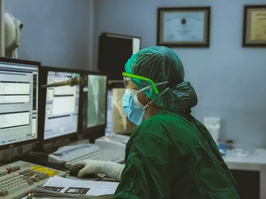 Doctor in a surgical suite and mask using artificial intelligence on a computer